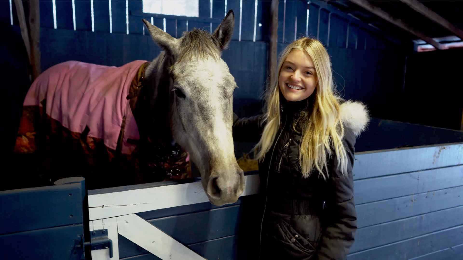 Willow standing next to a stall with one of her horses.