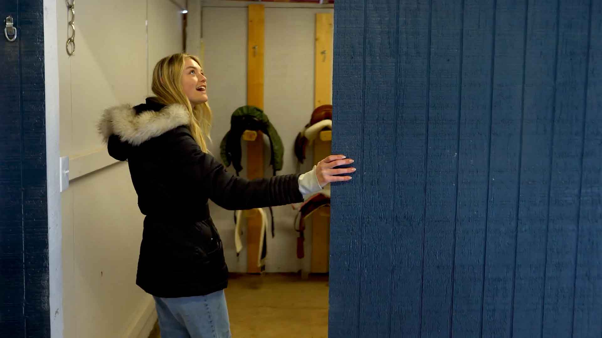 Willow Hand entering the tack room of her horse barn.