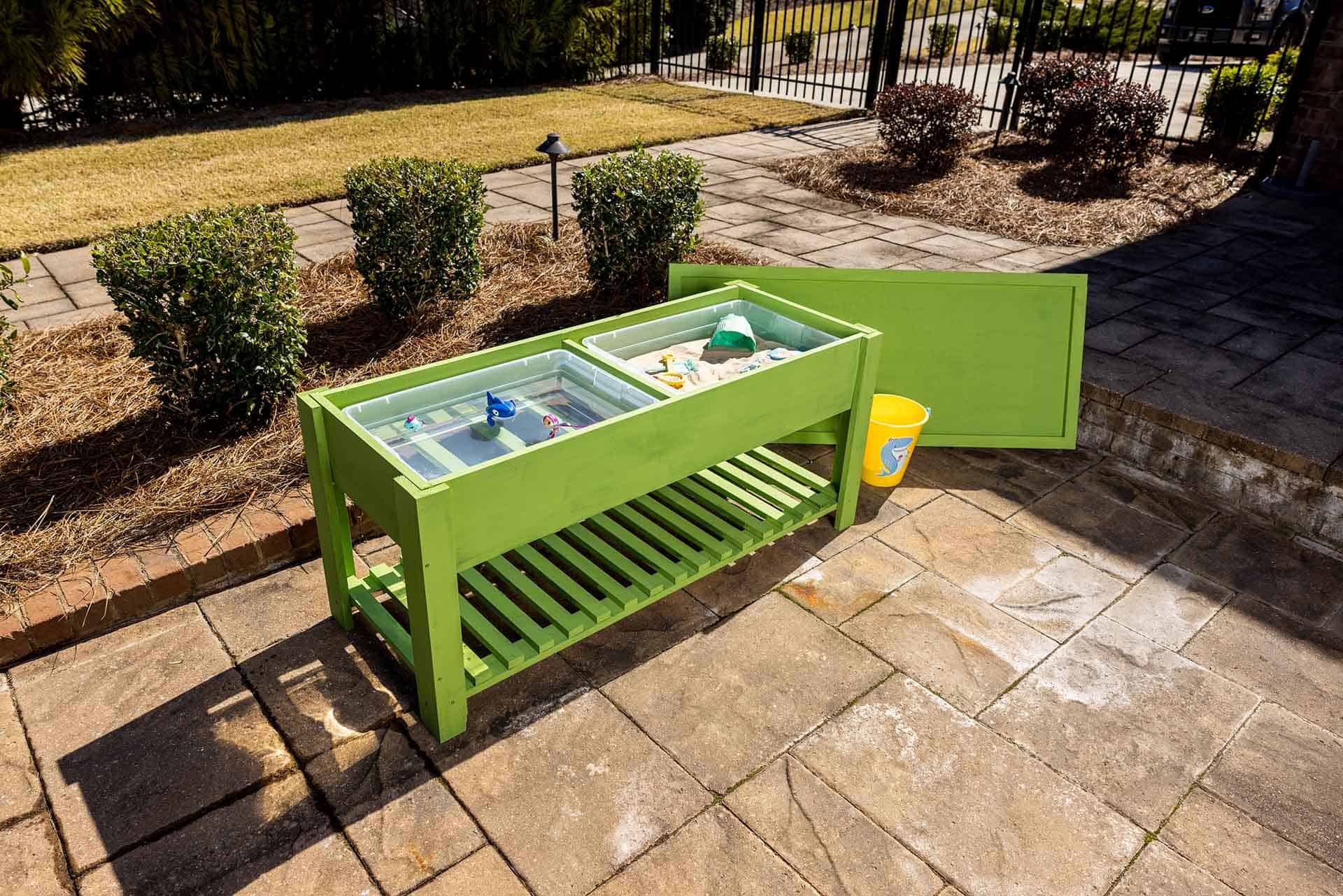Green sandbox table with toys inside