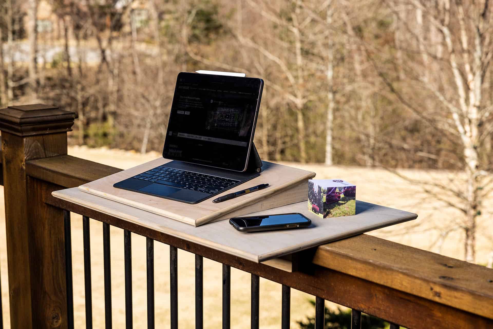 Finished Wooden tech desk on outdoor railing with laptop and phone
