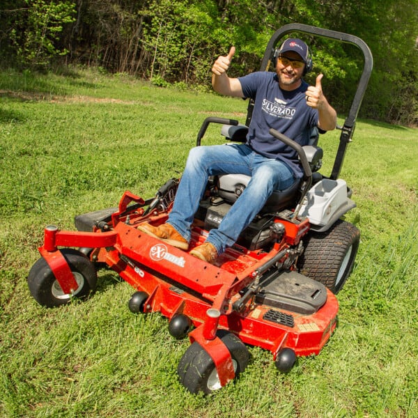 Michael Waddell giving thumbs up sitting on mower in field