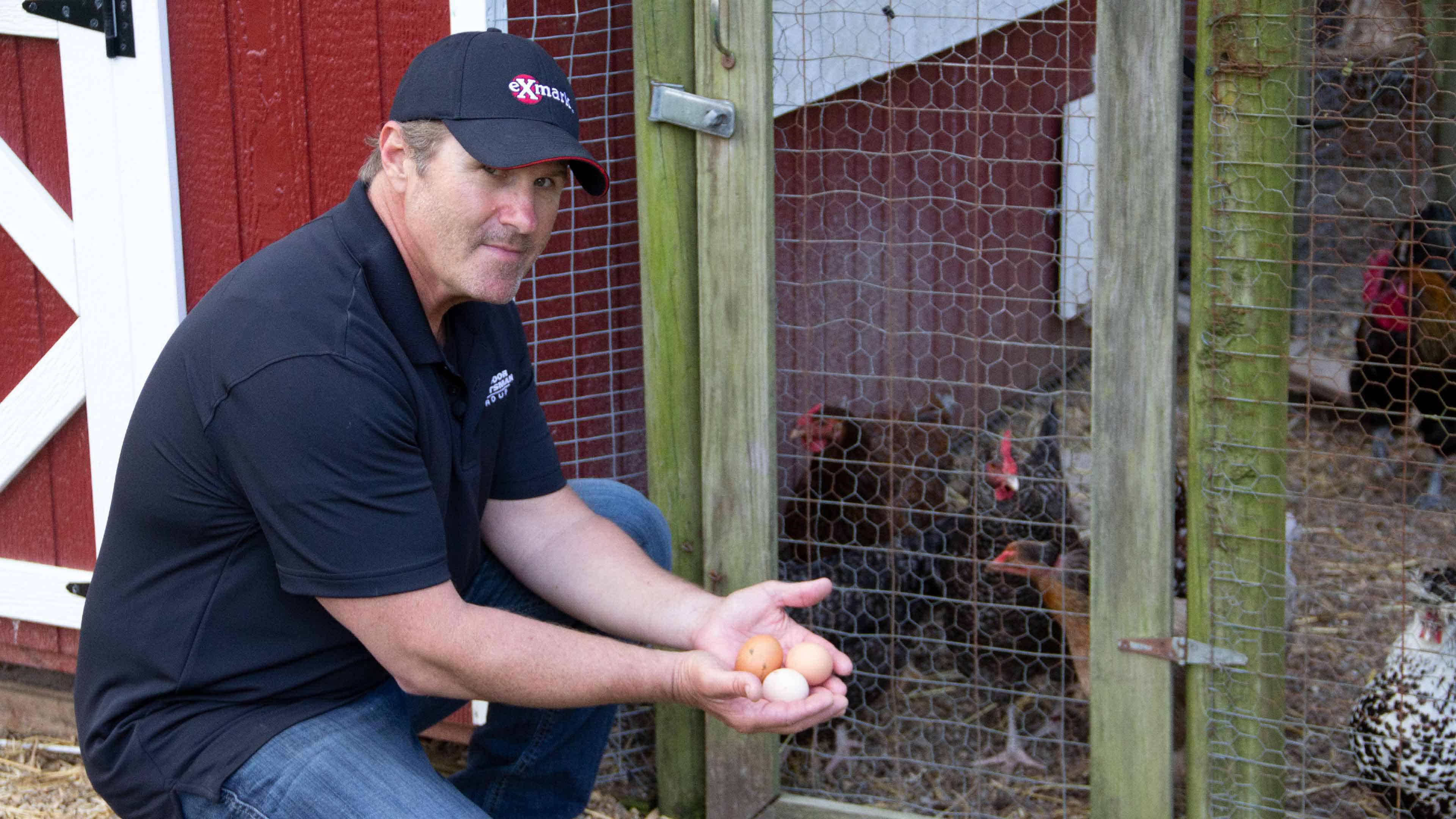 Joe holding chicken eggs in front of coop
