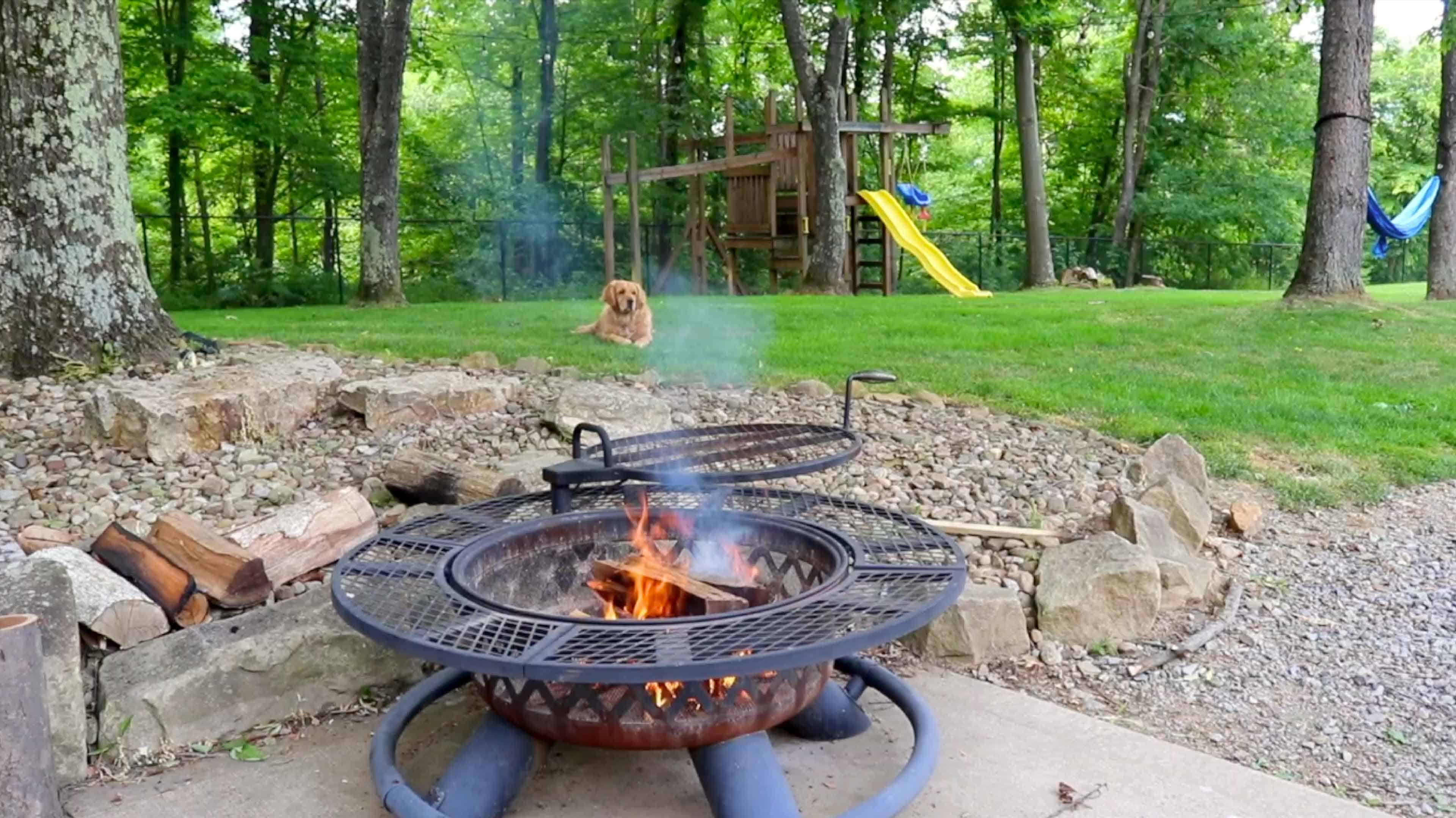 Campfire on patio with dog laying in grass