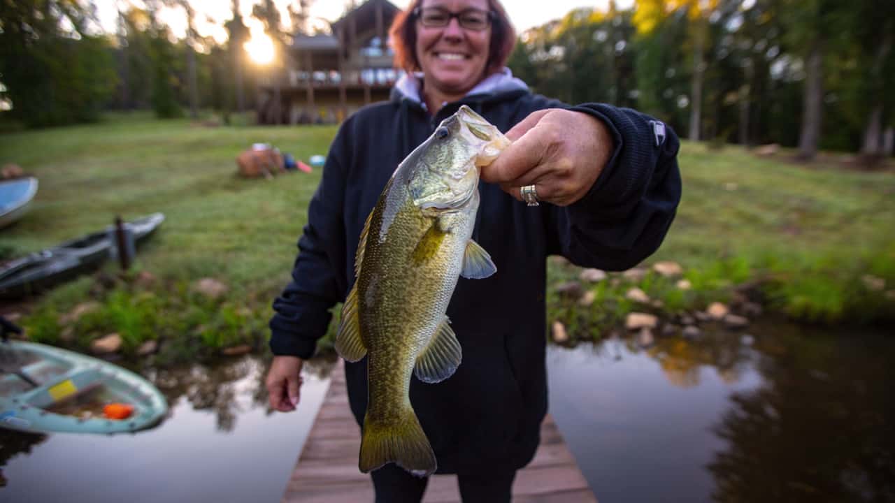 Woman holding fish caught from pond