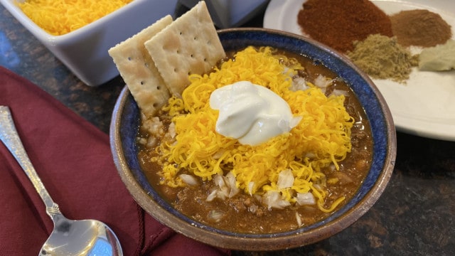 Bowl of chili with cheese, sour cream, and crackers