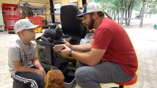 Man teaching kid how to care for mower