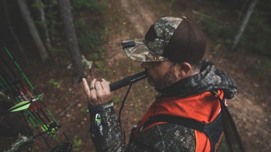 Man using a hunting call in the woods
