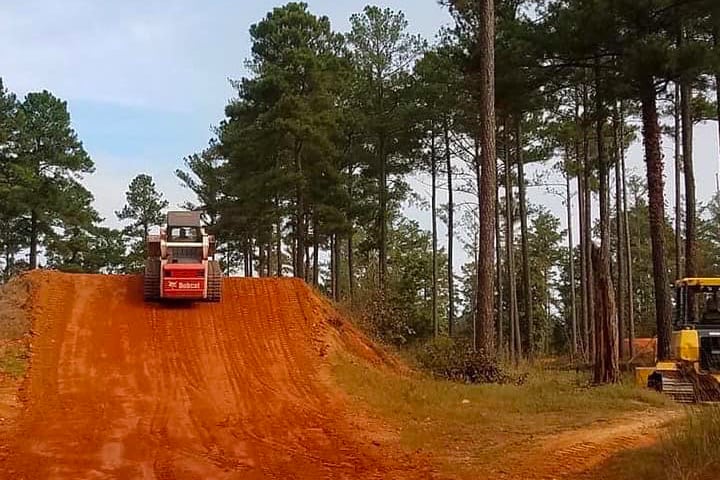 Heavy machinery shaping a dirt hill