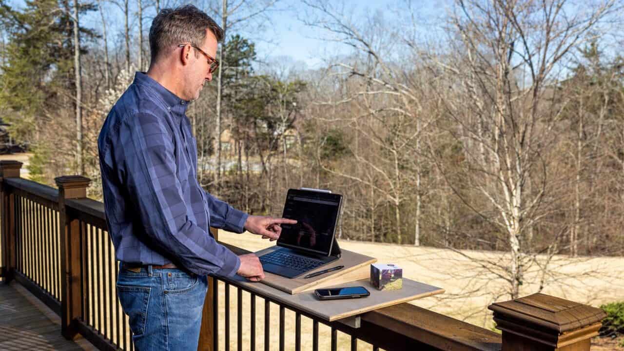 Doug Scott with laptop desk on deck railing