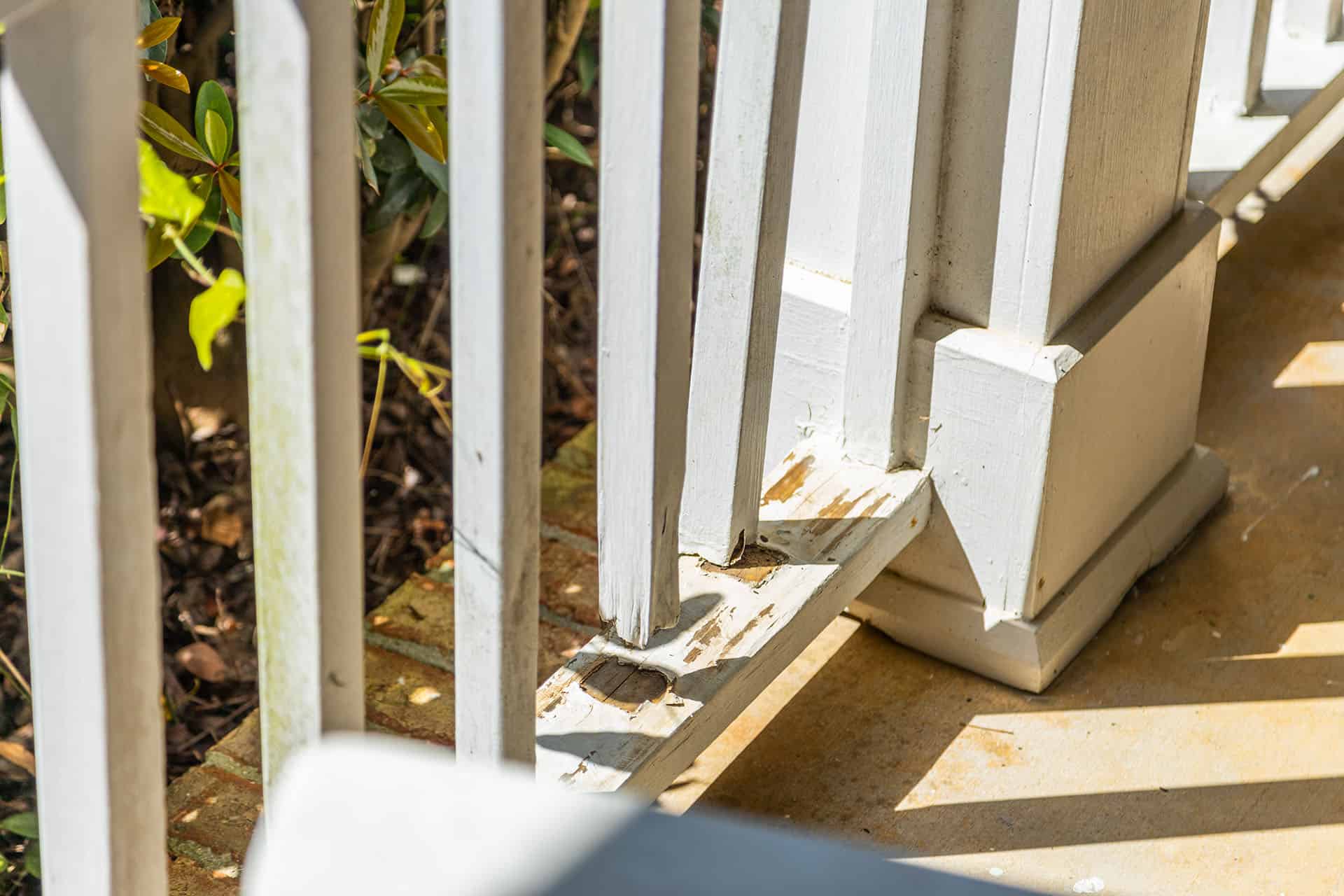 A wooden railing with rot at the bottom