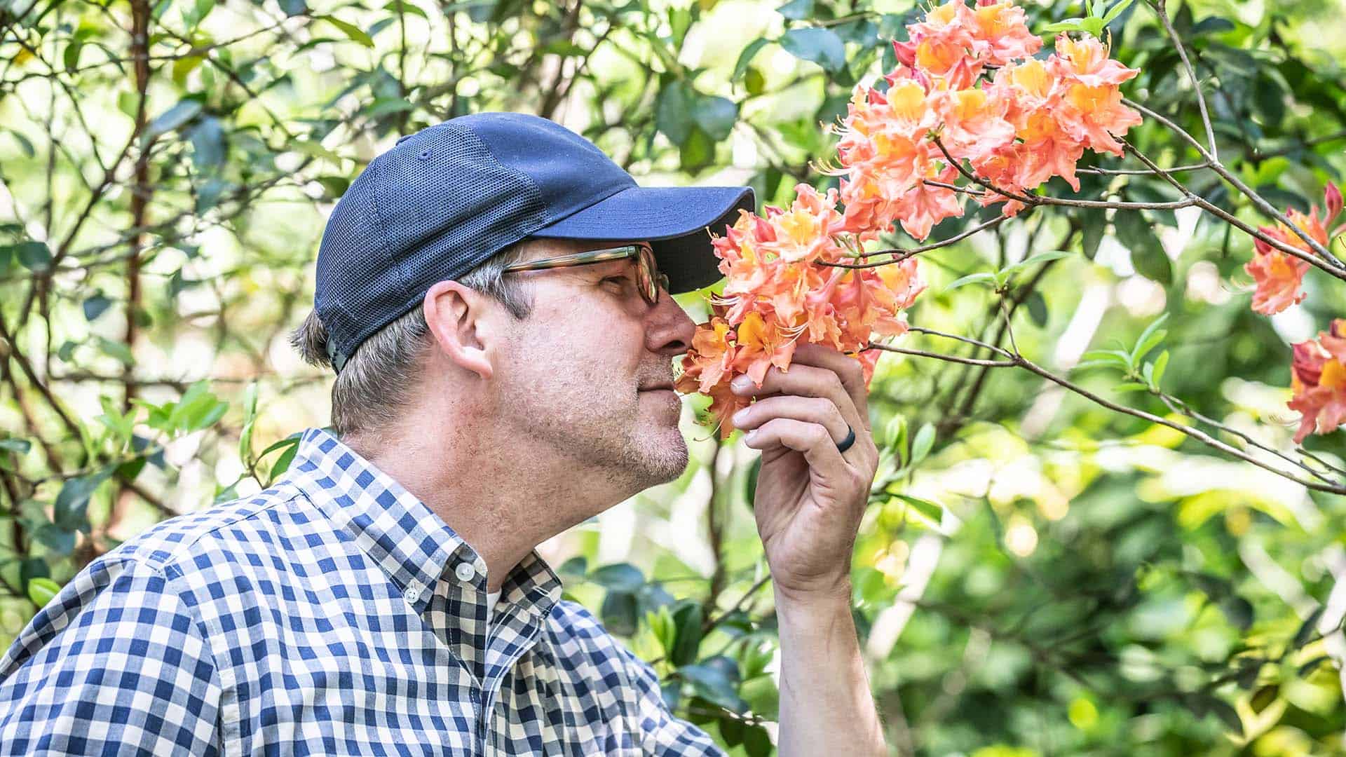 Doug Scott smelling orange flowers from a tree in mental health garden