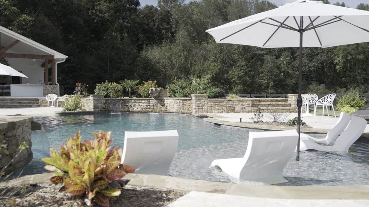Pool with chairs, umbrella, and plants
