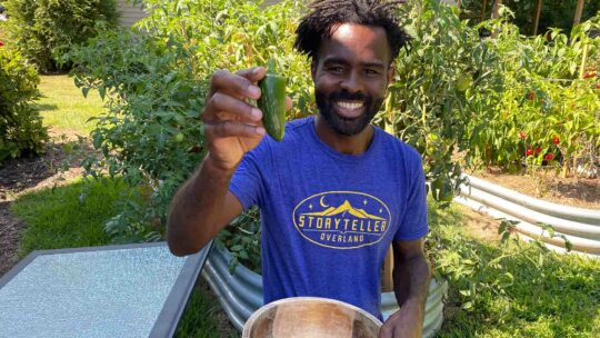 Brian Latimer holding up one of his backyard garden vegetables